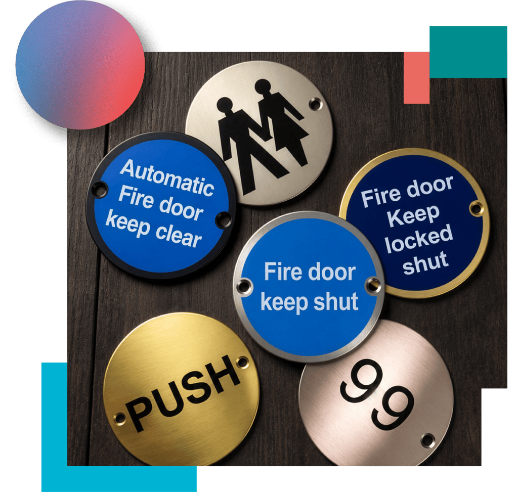 Group of metal door discs in stainless steel, brass, black and blue finishes on dark burnished timber.
